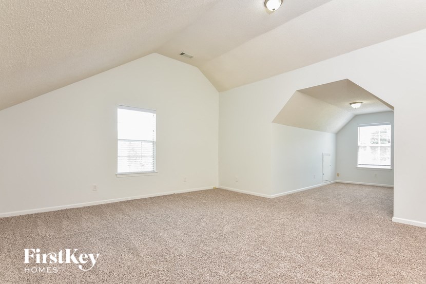 a spacious attic room with carpeting and a window