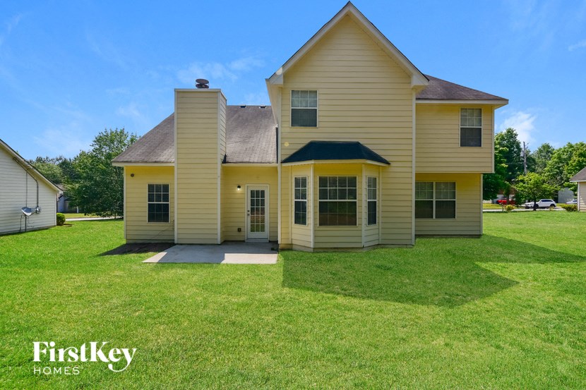 the front of a yellow house with a grassy yard