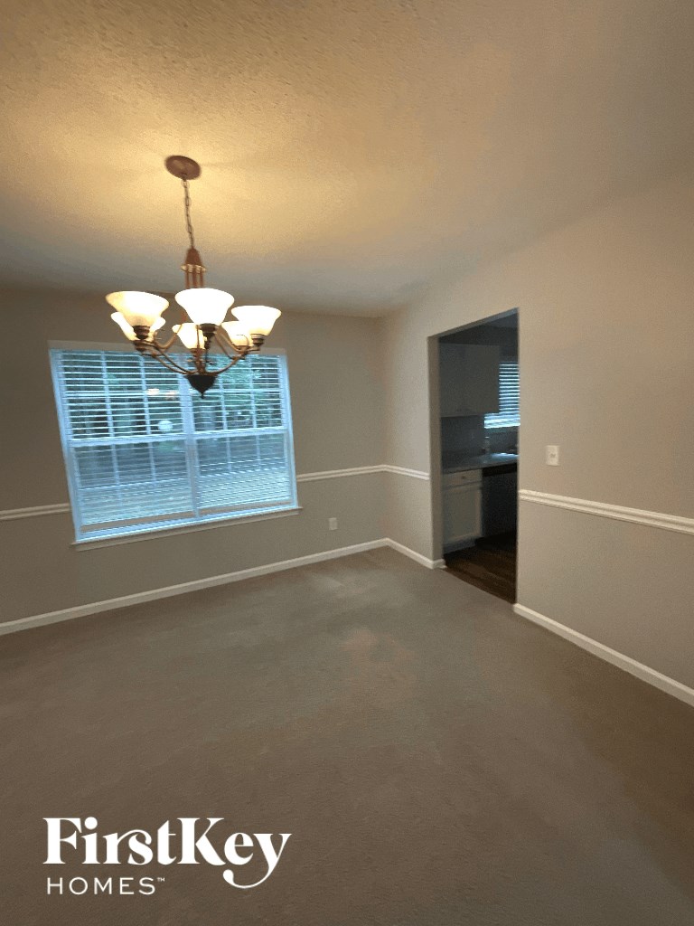 an empty living room with a chandelier and a window
