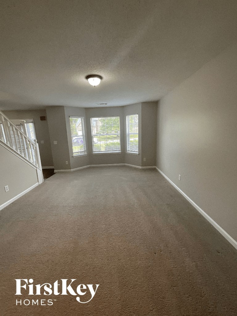 an empty living room with carpet and windows