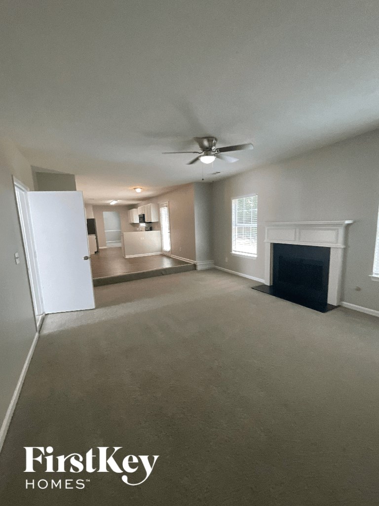 an empty living room with a ceiling fan and a fireplace