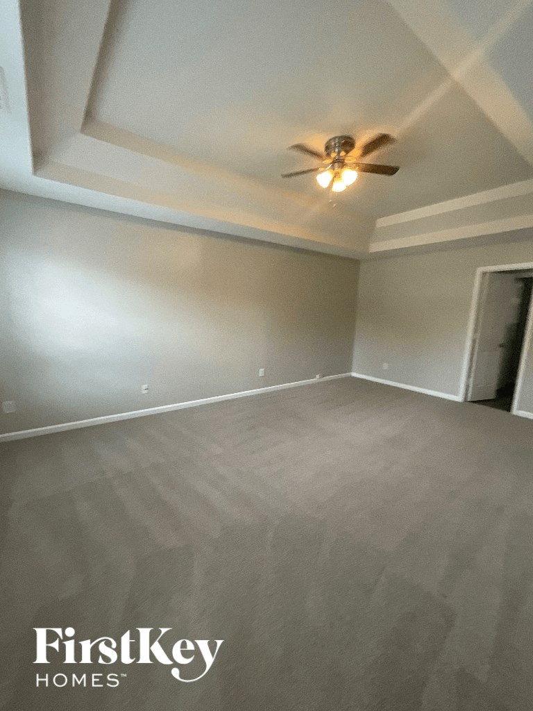an empty living room with a ceiling fan and white walls
