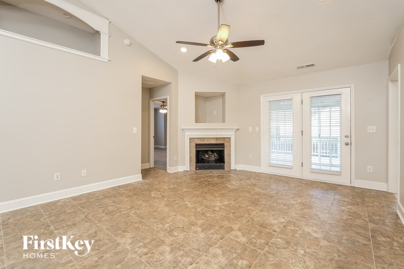 A spacious living room with a fireplace and a ceiling fan.