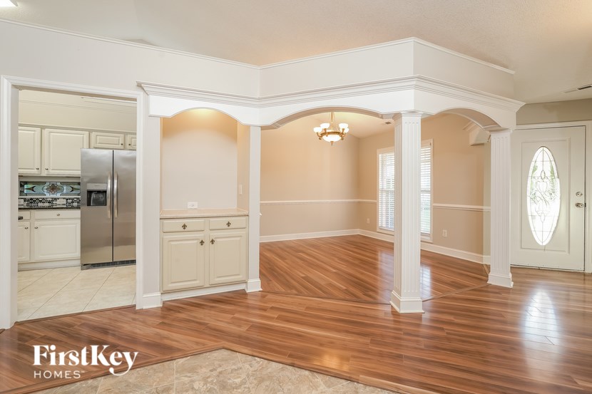 A spacious kitchen with wooden floors and white walls.