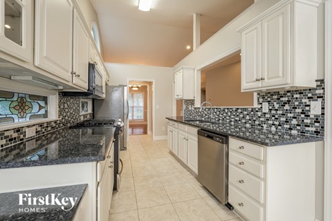 A kitchen with white cabinets and a black counter top.