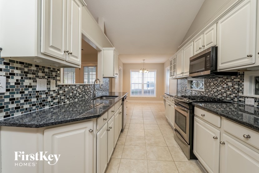 A kitchen with white cabinets and black countertops.