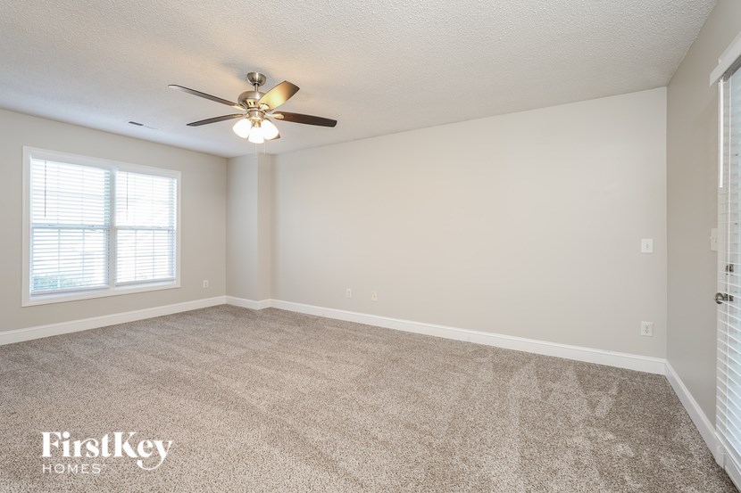 A room with a ceiling fan and carpeted floor.