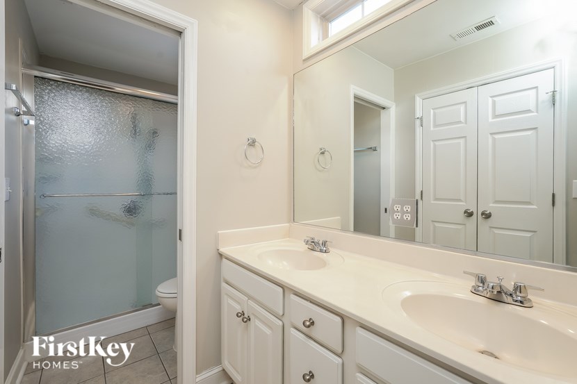 A bathroom with a sink, mirror, and shower.