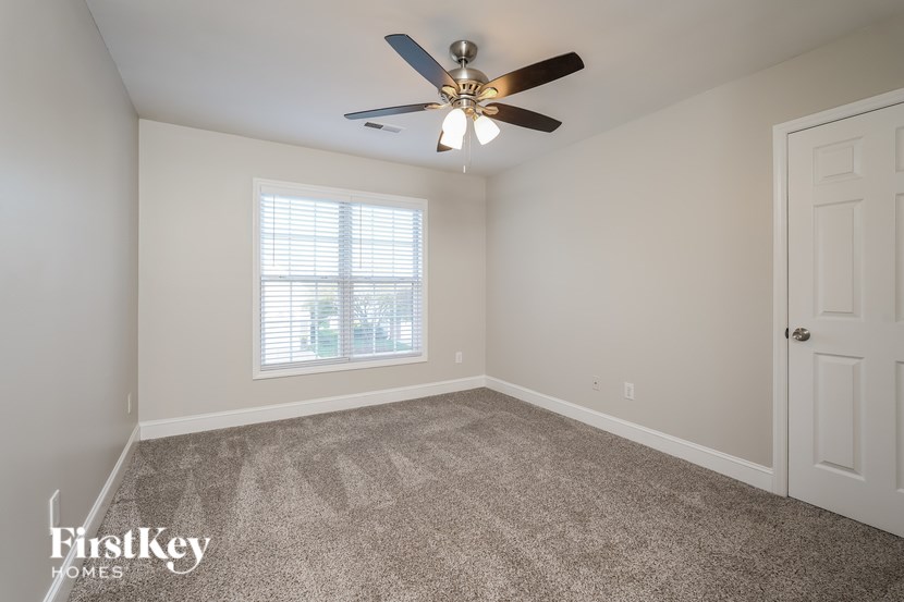 A room with a ceiling fan and a window with blinds.