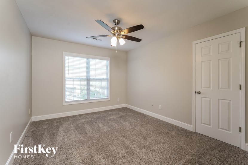 A room with a ceiling fan and a window with blinds.