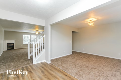A spacious room with a staircase and a fireplace.
