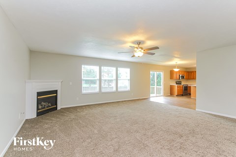 A spacious living room with a fireplace and a ceiling fan.
