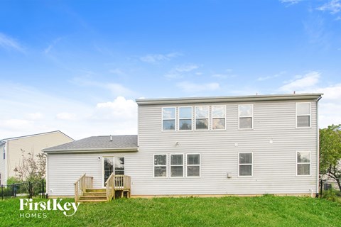 A house with a grassy front yard and a clear blue sky above.