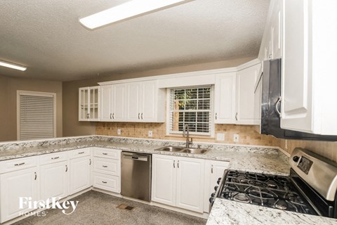 A kitchen with white cabinets and a granite countertop.