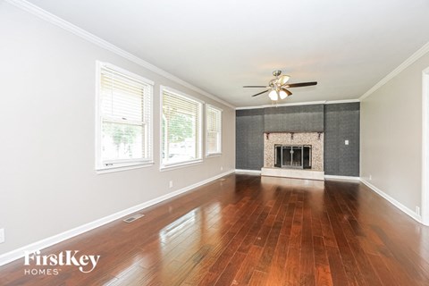 an empty living room with a fireplace and a ceiling fan