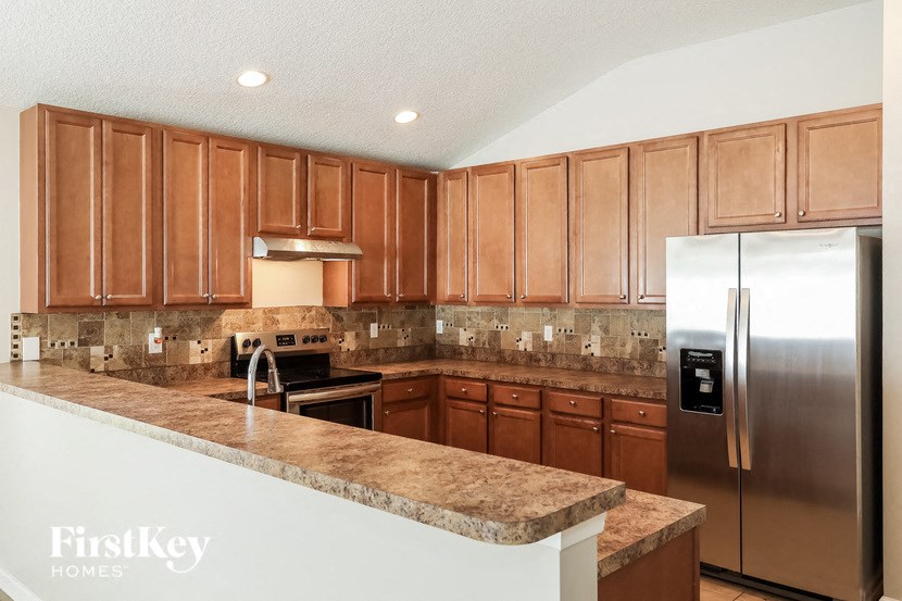 A kitchen with wooden cabinets and a marble counter top.