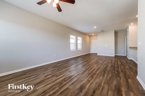 A spacious room with wooden flooring and a ceiling fan.