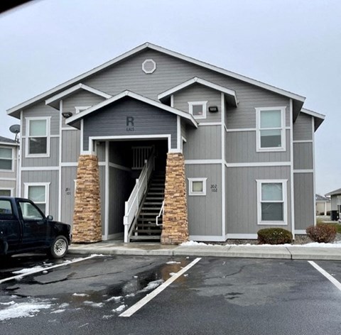 A grey building with a black truck parked in front.
