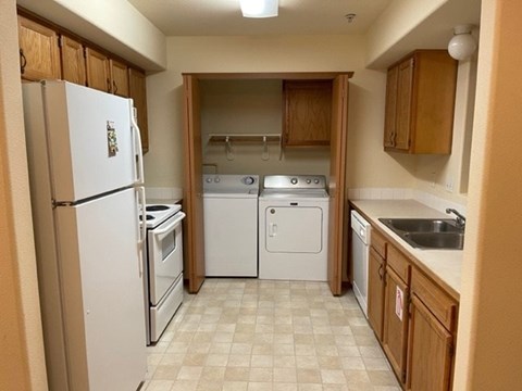 A kitchen with a white refrigerator, a dishwasher, a stove, and a sink.