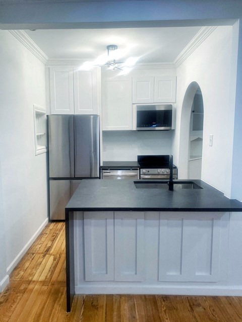 a kitchen with white cabinets and a black counter top