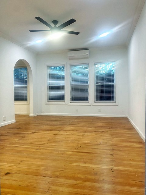 an empty living room with wood floors and a ceiling fan