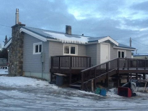 A house with a snow-covered roof and a wooden deck.