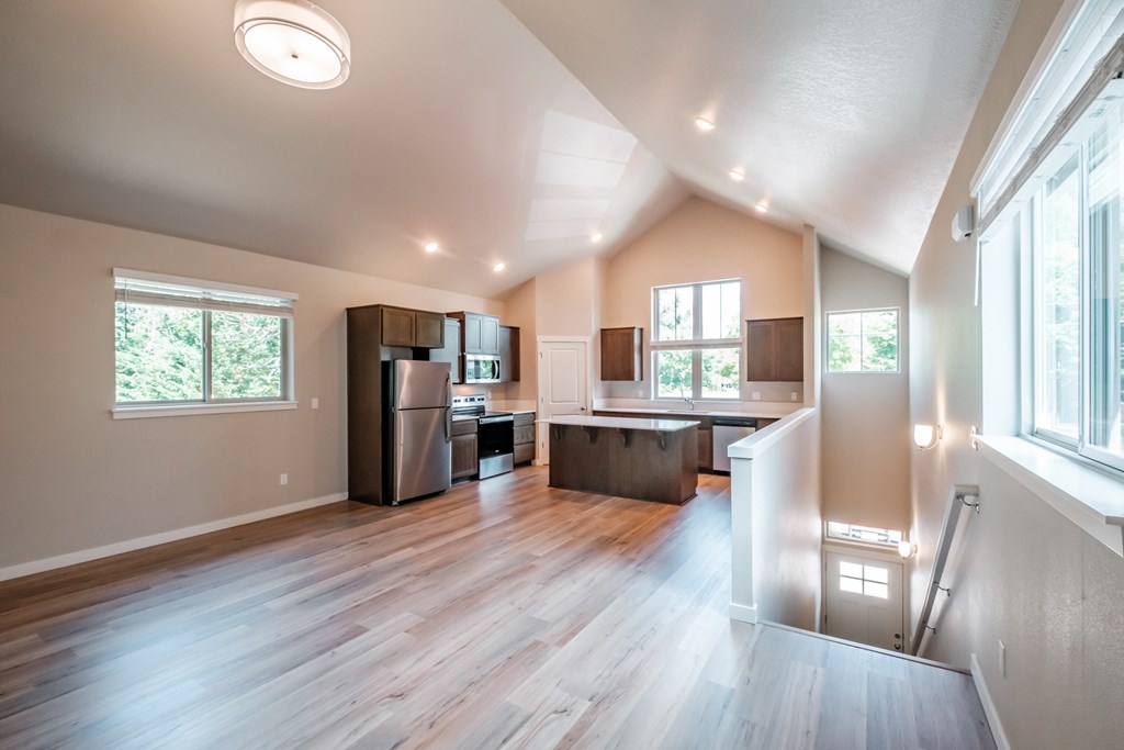 an open kitchen and living room with wood floors and a large window