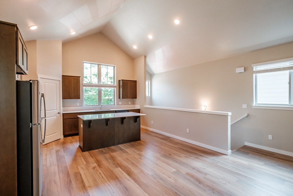 an empty kitchen with hardwood floors and a large window