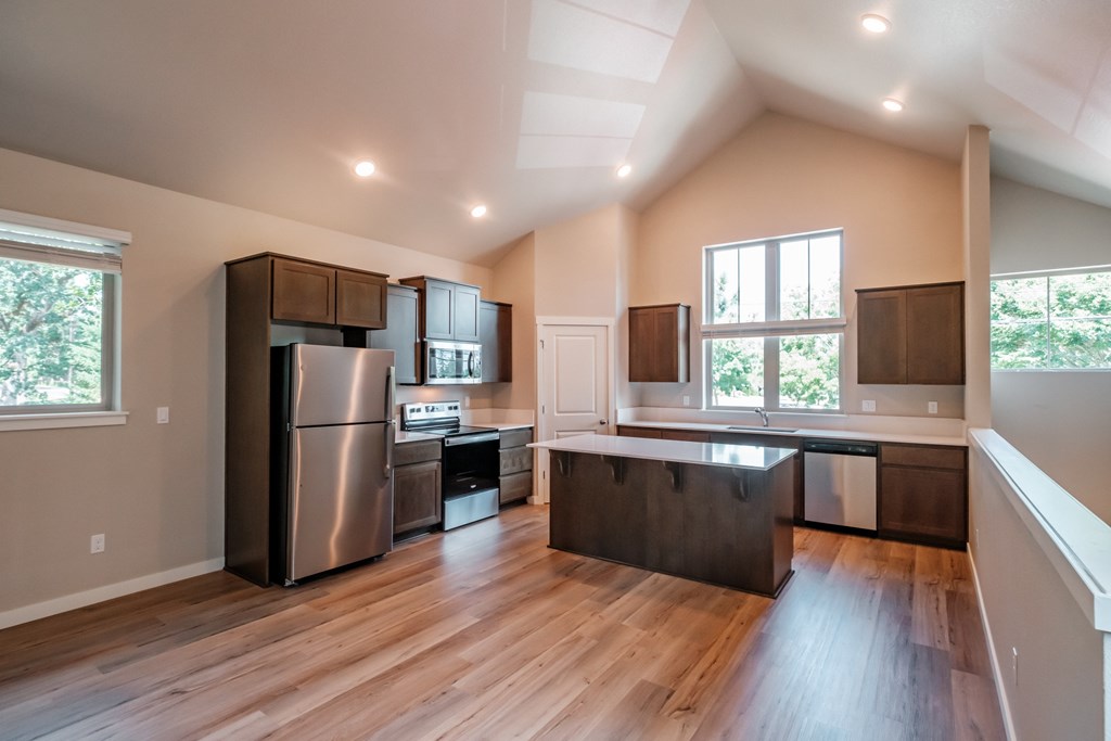 an open kitchen with stainless steel appliances and wooden floors