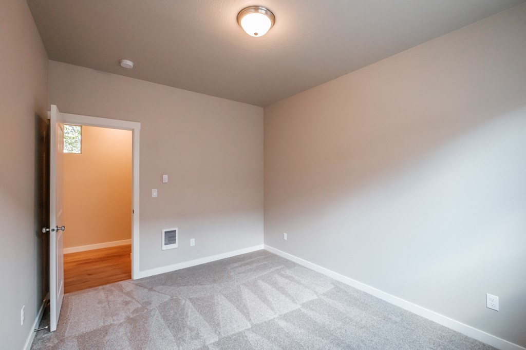 an empty room with white carpet and a door to a hallway