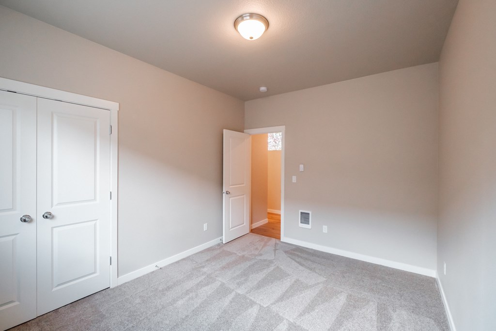 an empty bedroom with white doors and a carpeted floor