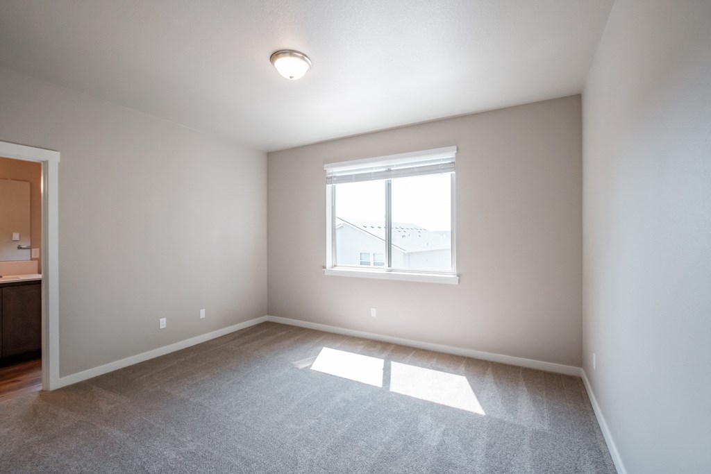 an empty living room with a large window and carpet