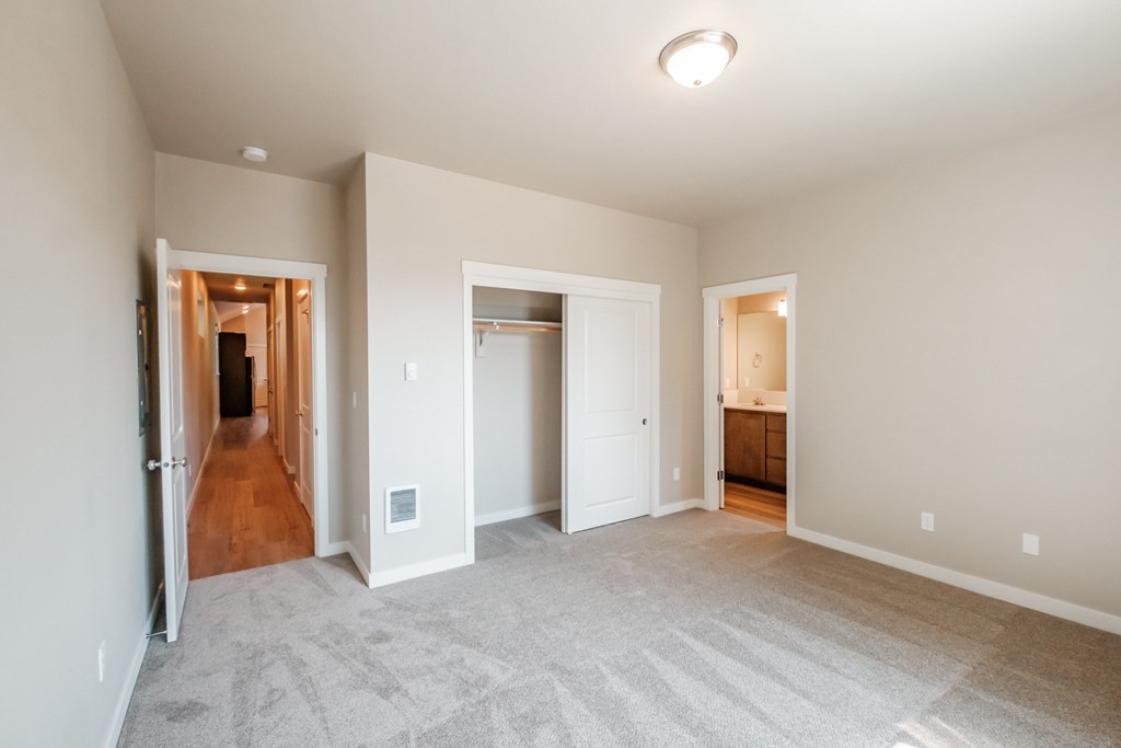 an empty living room with a hallway to a bedroom and a bathroom