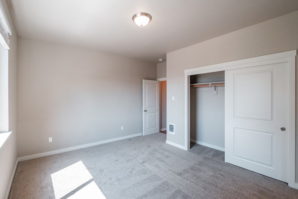 an empty living room with a closet and a door to a wardrobe