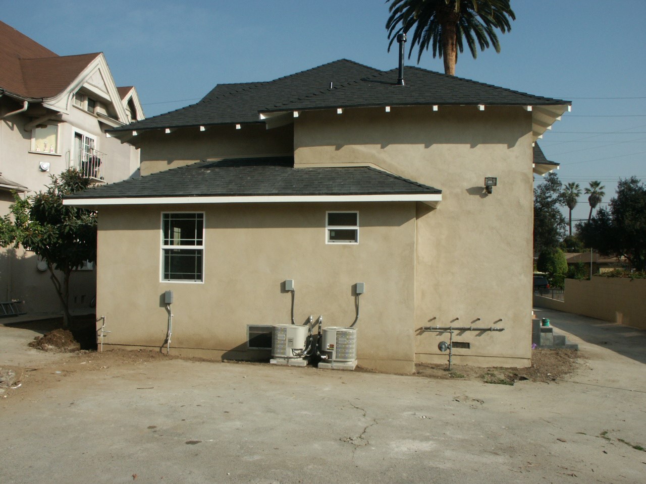 A house with a brown roof and tan walls with a tree in front of it.
