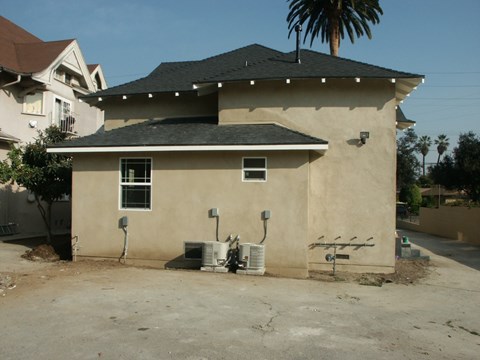 A house with a brown roof and tan walls with a tree in front of it.
