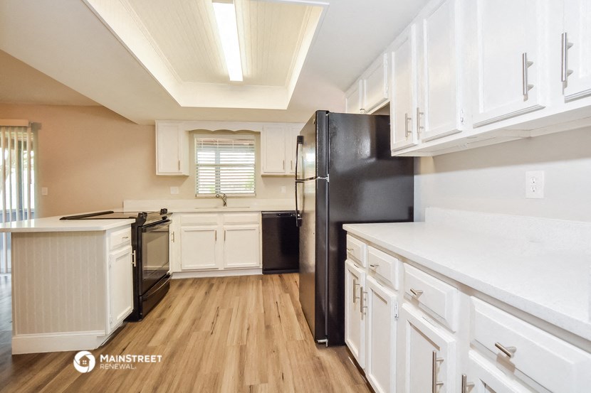 a kitchen with white cabinets and a black refrigerator
