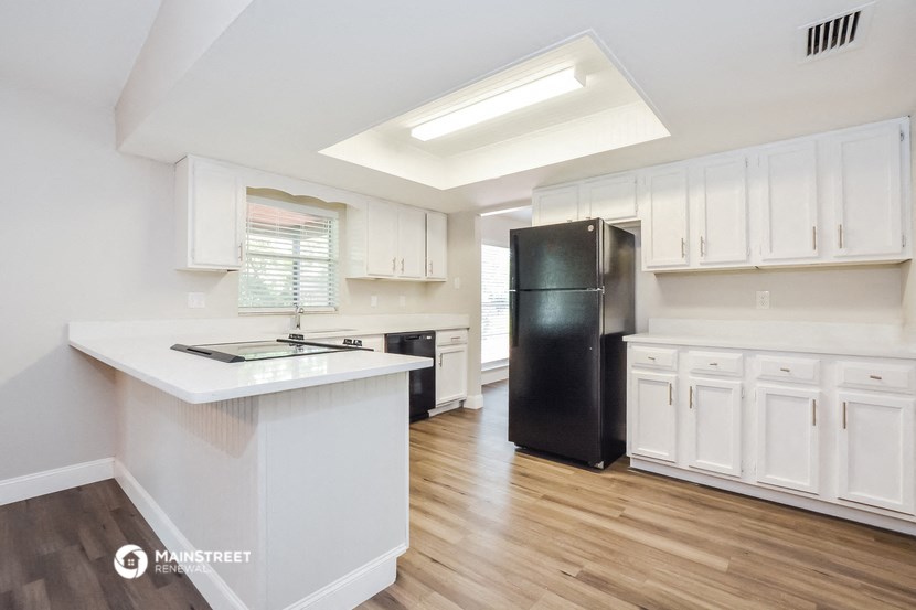 a kitchen with white cabinets and a black refrigerator