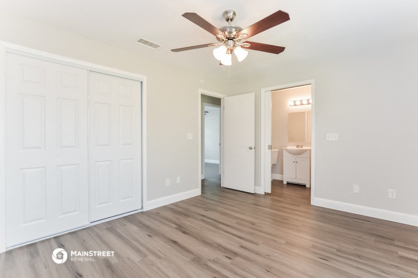a living room with white walls and a ceiling fan