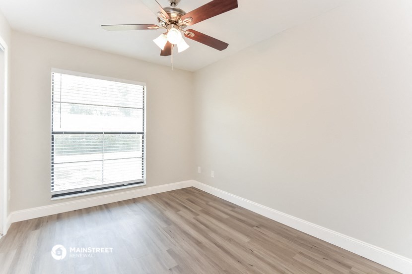an empty bedroom with a ceiling fan and a window
