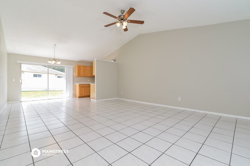 the spacious living room with tile flooring and a ceiling fan