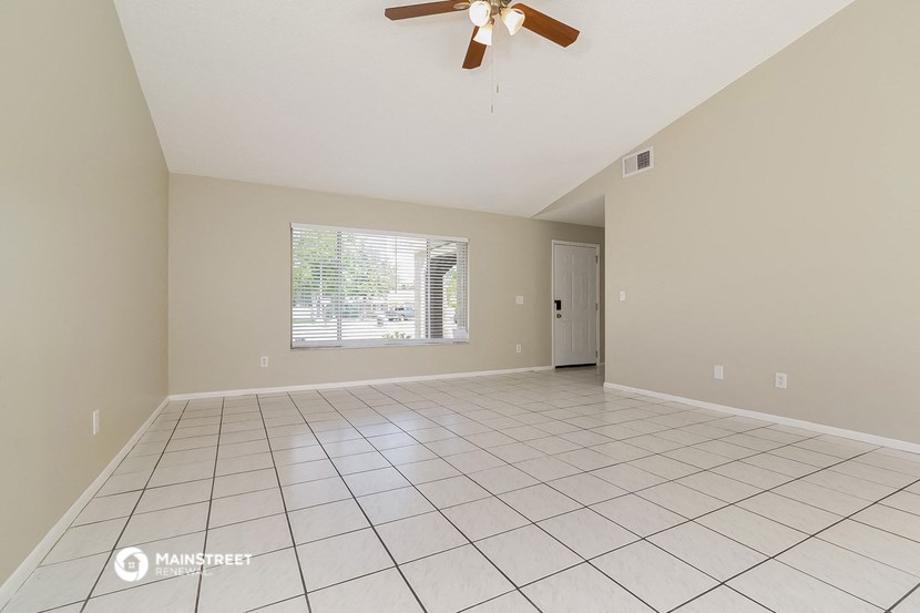 the spacious living room has tile flooring and a ceiling fan