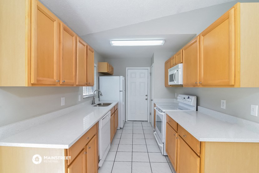a kitchen with white counter tops and wooden cabinets and a white refrigerator