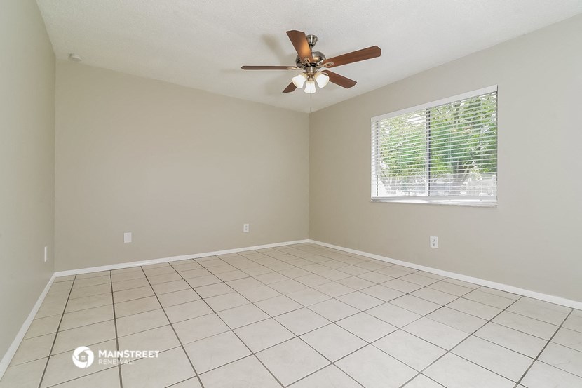 the spacious living room has a ceiling fan and tile flooring