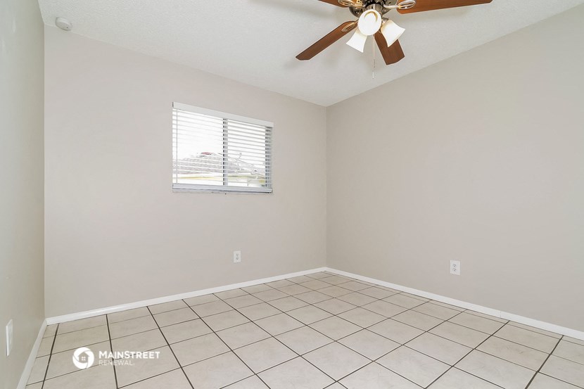 the living room has a ceiling fan and a tiled floor