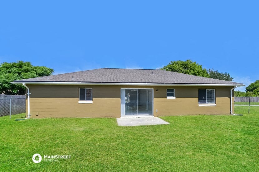 a yellow house with a grassy yard and a fence