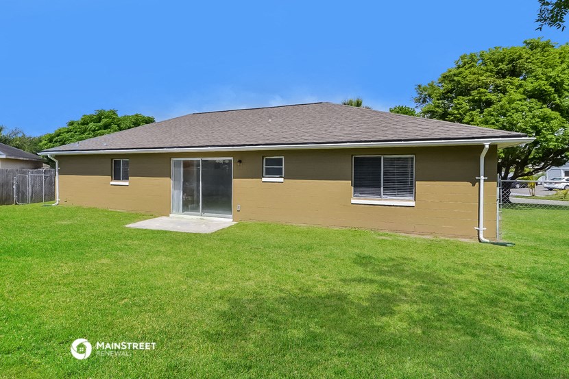 the front of a yellow house with a grassy yard