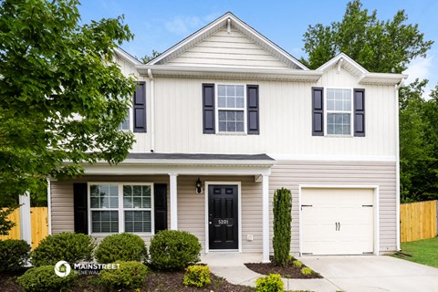 a white house with black window shutters and a driveway