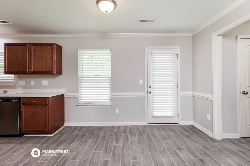 the kitchen and living room of a new home with white walls and wood flooring