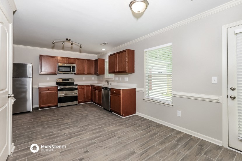 a kitchen with wood flooring and wooden cabinets and stainless steel appliances